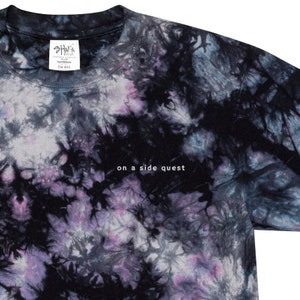 May include: Black tie-dye t-shirt with the text "on a side quest" printed on the front. The shirt has a faded, vintage look.