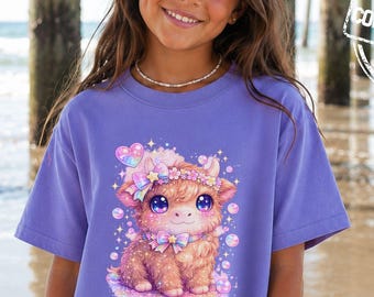 May include: A violet short-sleeve t-shirt featuring a graphic print of a fluffy brown highland cow with large purple eyes, a pastel bow, and sparkling bubbles. The shirt has a crew neckline and a relaxed fit, with the text COMFORT COLORS printed.