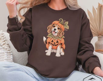 May include: A dark brown long-sleeve sweatshirt featuring a graphic illustration of a beagle puppy wearing a pumpkin costume with a matching hat. The puppy has a happy expression with its tongue out. The sweatshirt has a crew neckline and long sleeves.