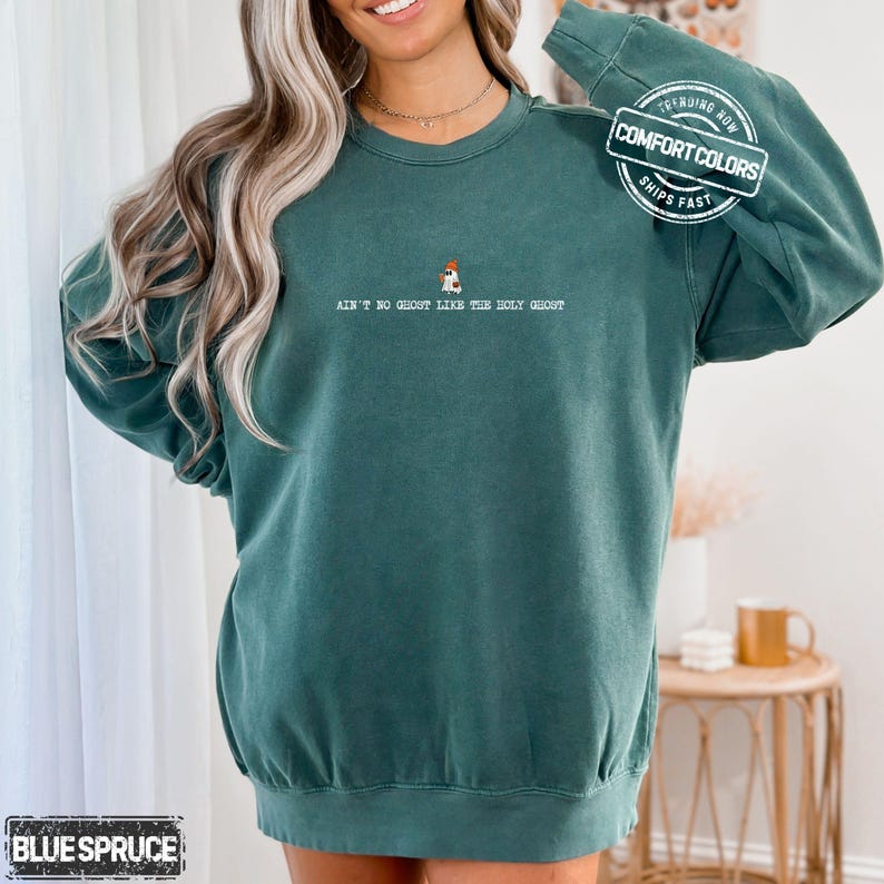 May include: Teal Comfort Colors sweatshirt with the text "AIN'T NO GHOST LIKE THE HOLY GHOST" and a small graphic. The sweatshirt has a crew neck and long sleeves. The image also includes the text "TRENDING NOW" and "SHIPS FAST".