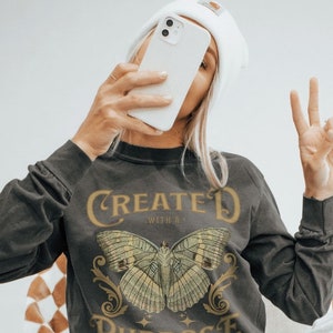 May include: A grey long-sleeved shirt with a butterfly graphic and the text "Created with a Purpose - Ephesians 2:10".