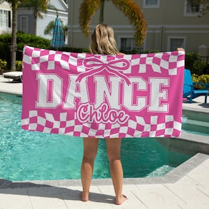 May include: A pink and white checkered dance towel with the word "DANCE" in large white block letters and the name "Chloe" in cursive. A bow graphic is above the word "DANCE".