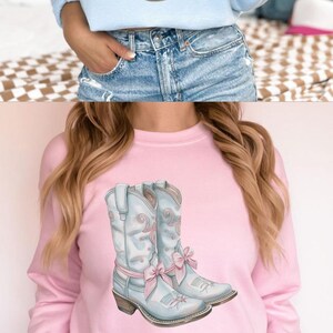 May include: Three different color sweatshirts featuring a pair of light blue cowboy boots with pink bows. The text "Coquette COWGIRL SWEATSHIRTS" is at the top of the image.