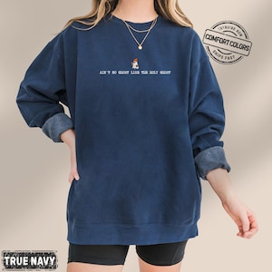 May include: A navy blue sweatshirt with the text "AIN'T NO GHOST LIKE THE HOLY GHOST" and a small graphic. The sweatshirt is a Comfort Colors brand. The sleeves are rolled up.