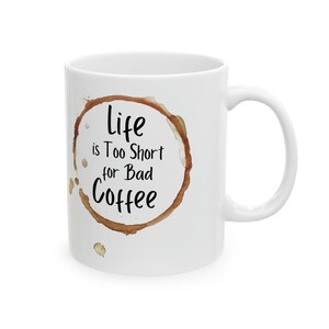 Puede incluir: Taza de café de cerámica blanca con una mancha de café marrón en forma de anillo y el texto "Life is Too Short for Bad Coffee".