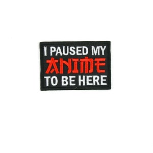 Könnte beinhalten: Schwarzer gestickter Aufnäher mit weißem Text, der "Ich habe meinen Anime pausiert, um hier zu sein" lautet, wobei das Wort "Anime" rot ist.