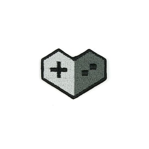 May include: A gray and white heart-shaped patch with a black embroidered gamepad design. The left side of the heart features a plus sign and the right side features a directional pad.