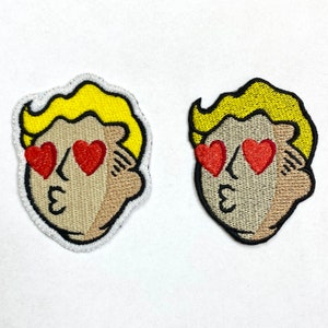 May include: Two embroidered patches of a cartoon character with yellow hair, brown skin, and red hearts for eyes. The character is making a kissy face. The text "3" is embroidered on the character's cheek.