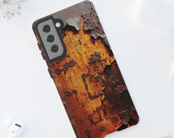 May include: A smartphone case with a textured, weathered appearance. The case features a rusty, orange, and brown color scheme, with a design that mimics the look of aged metal. The case has a camera module with three lenses and a black frame.