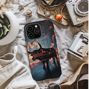 May include: A black phone case with a silhouette of a bull against a background of a stock market chart. The phone case has a camera lens cutout with three lenses.