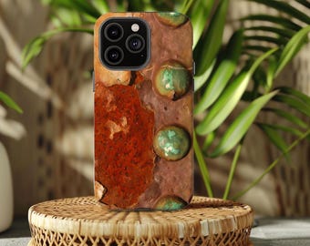 May include: A smartphone case with a weathered, rusty metal design. The case features a textured, reddish-brown surface with green, circular accents. The case is displayed on a small, round, woven wicker stand.