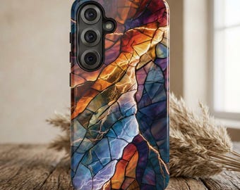 May include: A smartphone case featuring a vibrant, multi-colored stained glass pattern with deep blues, oranges, and purples. The design includes intricate geometric segments and lightning-like streaks. The case has a black camera module cutout.