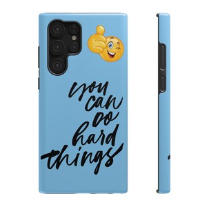 May include: A light blue phone case with a black and white graphic that says "you can do hard things". A yellow emoji with a thumbs up and a wink is in the top right corner.