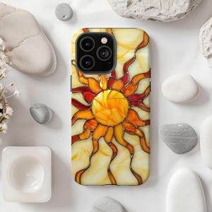 May include: A phone case with a stained glass design of a sun with orange, yellow, and red colors. The case has a black camera cutout.