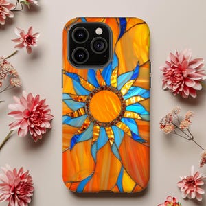 May include: A vibrant phone case featuring a stained-glass sun design. The case showcases a bright orange background with a blue and orange sunburst pattern. The sun's center is adorned with a ring of small, sparkling embellishments. The case is surrounded by pink flowers.