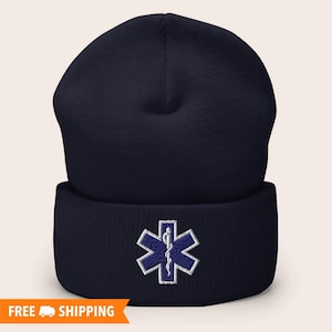 May include: A navy blue beanie with a white embroidered medical symbol, the Star of Life, on the front.