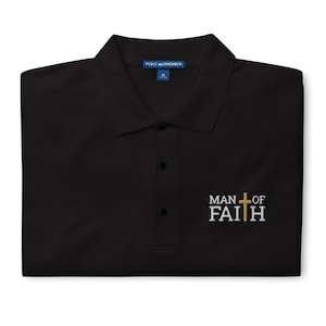 May include: Black polo shirt with a collared neckline and three-button placket. The shirt features the embroidered text "MAN OF FAITH" with a cross graphic. The shirt is a medium size.