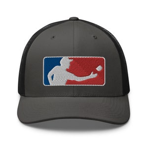 May include: A dark gray trucker hat with a black mesh back. The hat features an embroidered baseball logo with a white player throwing a ball. The logo has red, white, and blue accents.