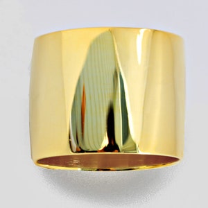 May include: A wide, gold band ring with a smooth, polished finish.