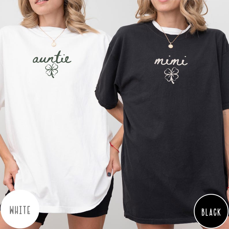 May include: Two oversized t-shirts, one white and one black. The white shirt has the word "auntie" and a shamrock graphic. The black shirt has the word "mimi" and a shamrock graphic. The word "WHITE" is printed on the bottom left of the white shirt, and "BLACK" is printed on the bottom right of the black shirt.