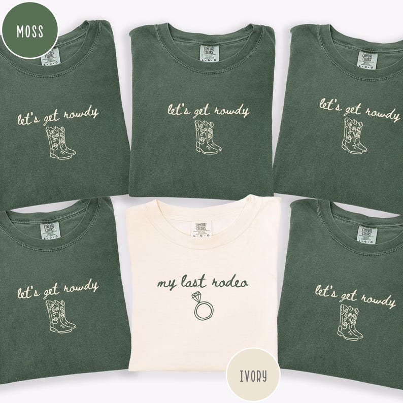 May include: Five short-sleeved crewneck t-shirts. Four shirts are moss green with white embroidered text reading let's get rowdy and a cowboy boot graphic. One shirt is ivory with black embroidered text reading my last rodeo and a diamond ring graphic.