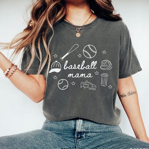 Puede incluir: Una camiseta gris con un dise&ntilde;o gr&aacute;fico blanco de equipo de b&eacute;isbol y el texto "baseball mama".