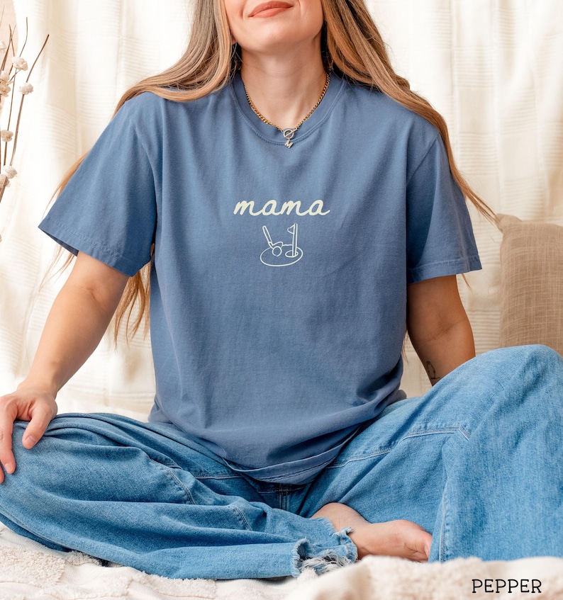 May include: A blue t-shirt with the text "mama" and a golf club and ball graphic.