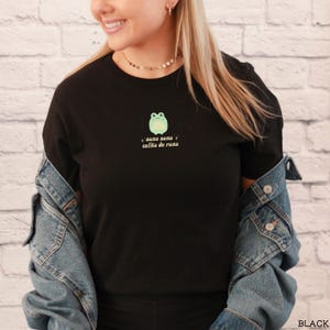 May include: Black t-shirt with a green frog graphic and the text "sana sana colita de rana" in white.