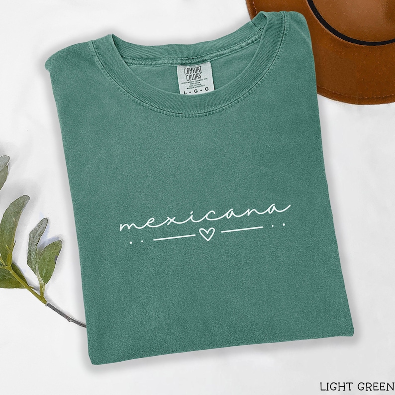May include: Light green t-shirt with the text "mexicana" in white with a small heart above a line.