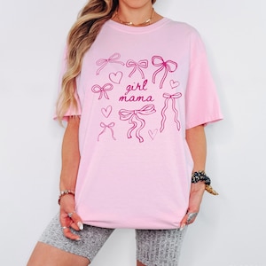 May include: Pink t-shirt with a graphic of pink bows and hearts and the text "girl mama".