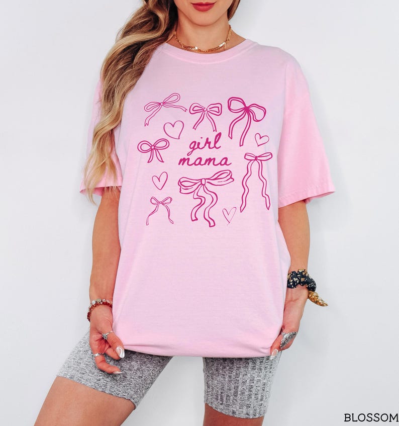 May include: Pink t-shirt with a graphic of pink bows and hearts and the text "girl mama".
