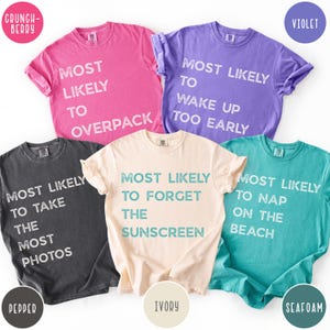 Puede incluir: Cinco camisetas de manga corta y cuello redondo en rosa, violeta, gris oscuro, marfil y verde espuma de mar. Cada camiseta presenta texto blanco con estilo desgastado. Las frases incluyen Most Likely To Overpack, Wake Up Too Early, Take The Most Photos, Forget The Sunscreen y Nap On The Beach.
