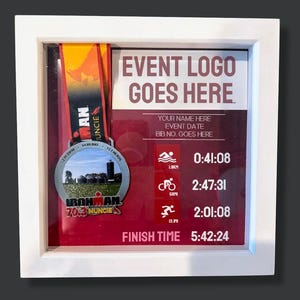 May include: A framed Ironman 70.3 Muncie race medal. The medal is silver with a colorful ribbon. The frame includes event details, such as the event logo, name, date, and finish times: 0:41:08, 2:47:31, and 2:01:08, with a total finish time of 5:42:24.