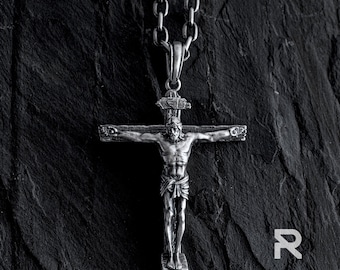 May include: Silver crucifix pendant necklace with a detailed depiction of Jesus Christ on the cross. The chain is silver and has a classic link design.