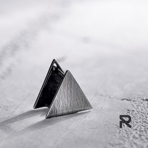 Puede incluir: Un par de pendientes triangulares de plata con acabado cepillado.