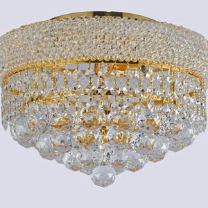 May include: A gold-toned, crystal chandelier with multiple tiers of sparkling, faceted crystals. The fixture has a rounded shape and is designed for ceiling mounting, offering a luxurious lighting option.