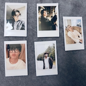 May include: Five instant photo prints featuring portraits of people in various settings. The photos are in white frames and show individuals in casual attire, some wearing glasses. The backgrounds vary from indoor settings to outdoor scenes.