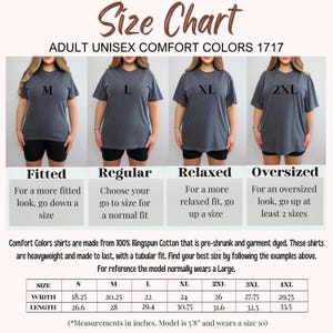 May include: A size chart for Comfort Colors 1717 adult unisex t-shirts. The image displays four variations of a charcoal gray t-shirt labeled M, L, XL, and 2XL, alongside a table listing width and length measurements in inches from S to 4XL.