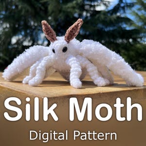 Könnte beinhalten: Eine handgefertigte weiße Seidenmotte mit braunen Fühlern und schwarzen Augen. Die Motte besteht aus flauschigem Material und hat sechs Beine und große Flügel. Der Text "Silk Moth" und "Digital Pattern" ist darunter zu sehen.