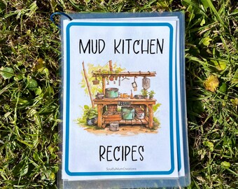 May include: A clear plastic sleeve containing a recipe book. The cover features the words "MUD KITCHEN RECIPES" in black font, with an illustration of a wooden outdoor kitchen. The book is resting on a bed of green grass.