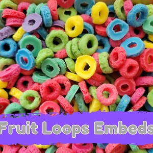 May include: A close-up of colorful, ring-shaped cereal pieces. The cereal is in various colors, including red, yellow, green, blue, and purple. The text "Fruit Loops Embeds" is displayed on a purple banner.