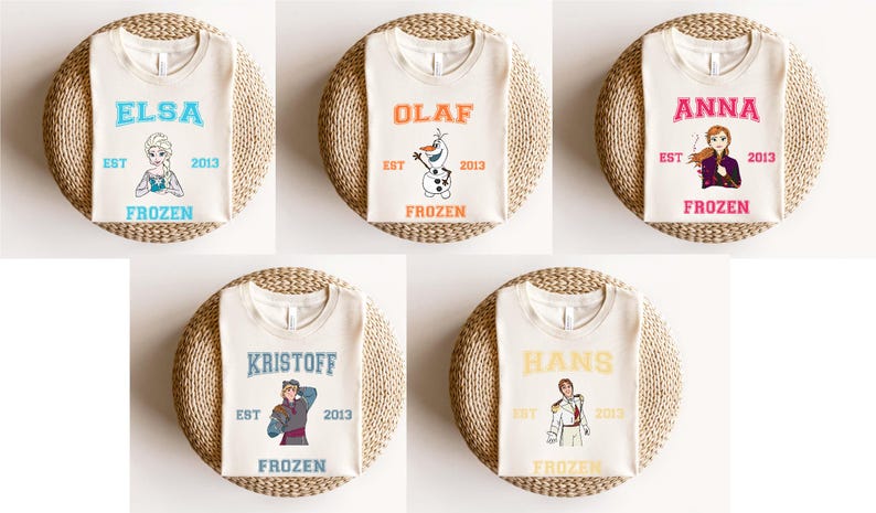 Puede incluir: Cinco camisetas blancas con diferentes personajes de Frozen impresos en ellas. Los personajes son Elsa, Olaf, Anna, Kristoff y Hans. Cada camiseta tiene el texto "EST" y "FROZEN" impreso en ella.