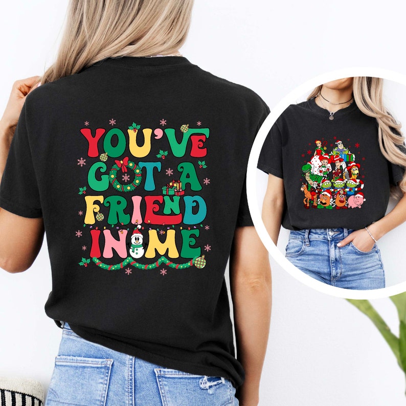 Peut inclure: T-shirt noir avec un motif color&eacute; qui dit "You've Got A Friend In Me" avec un bonhomme de neige et des lumi&egrave;res de No&euml;l. Le t-shirt est port&eacute; par une personne.