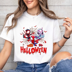 Peut inclure: T-shirt blanc avec un motif de trois personnages de Spider-Man en dessin anim&eacute; dans une toile d'araign&eacute;e avec des citrouilles et des chauves-souris. Le texte "Happy Halloween" est sous les personnages.