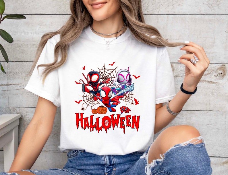 Peut inclure: T-shirt blanc avec un motif de trois personnages de Spider-Man en dessin anim&eacute; dans une toile d'araign&eacute;e avec des citrouilles et des chauves-souris. Le texte "Happy Halloween" est sous les personnages.
