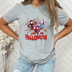 Peut inclure: Un t-shirt gris avec un motif de trois personnages Spider-Man dans une toile d'araign&eacute;e avec des citrouilles et le texte "Happy Halloween".