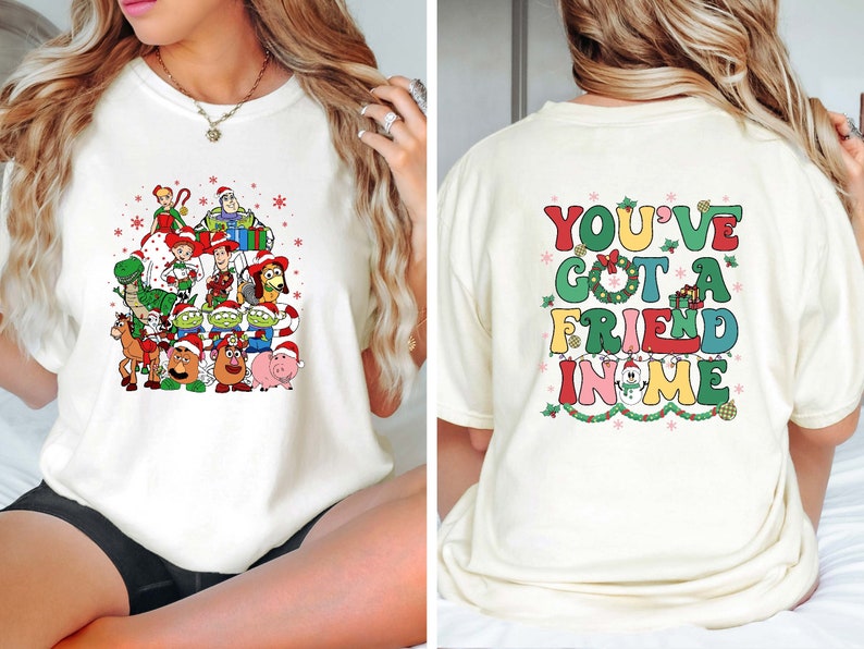 Peut inclure: T-shirt blanc avec un motif d'arbre de No&euml;l repr&eacute;sentant des personnages de la franchise de films Toy Story. Le dos du t-shirt porte le texte "You've got a friend in me" en lettres color&eacute;es.