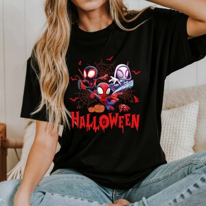 Peut inclure: T-shirt noir avec un motif de trois personnages Spider-Man dans une toile d'araign&eacute;e avec le mot "HALLOWEEN" en lettres rouges qui coulent.