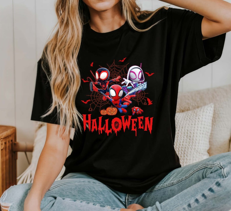 Peut inclure: T-shirt noir avec un motif de trois personnages Spider-Man dans une toile d'araign&eacute;e avec le mot "HALLOWEEN" en lettres rouges qui coulent.