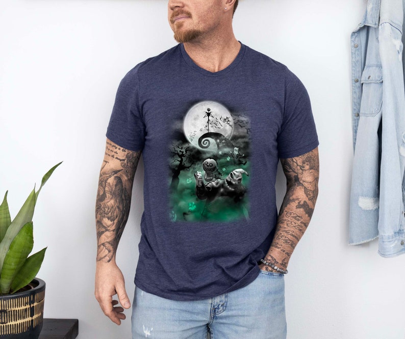 K&ouml;nnte beinhalten: Ein marineblaues T-Shirt mit einem Grafikdruck von Jack Skellington aus Nightmare Before Christmas. Die Grafik zeigt Jack Skellington, der auf einem H&uuml;gel steht, mit einem Vollmond hinter ihm.